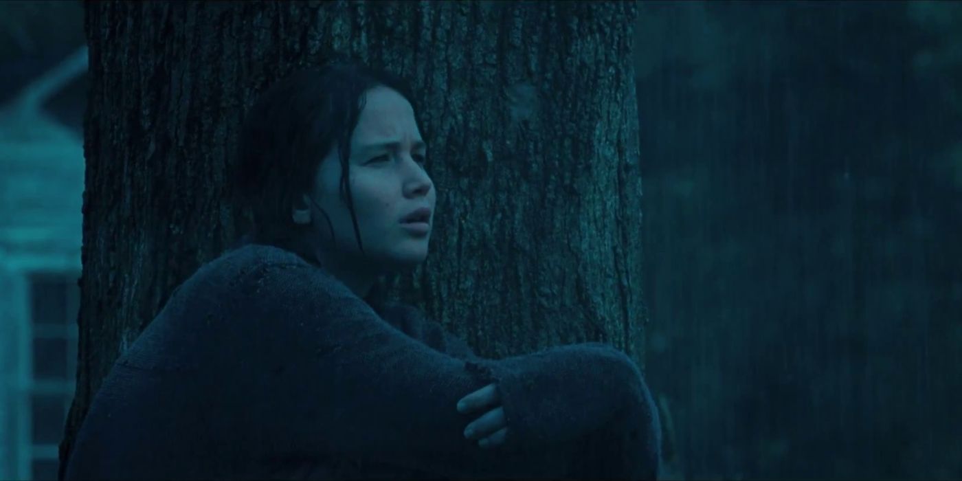 Katniss Everdeen in the rain sat against a tree before Peeta gives her bread in The Hunger Games