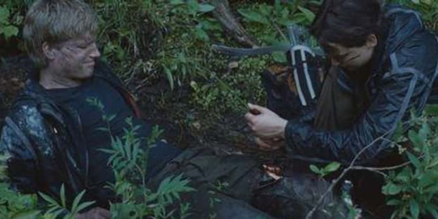 Katniss helping Peeta with his injured leg in The Hunger Games