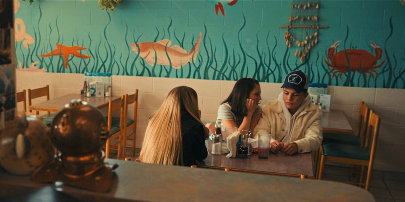 Warren, Josephine, and Kelly sit at a table in a diner in Under the Bridge