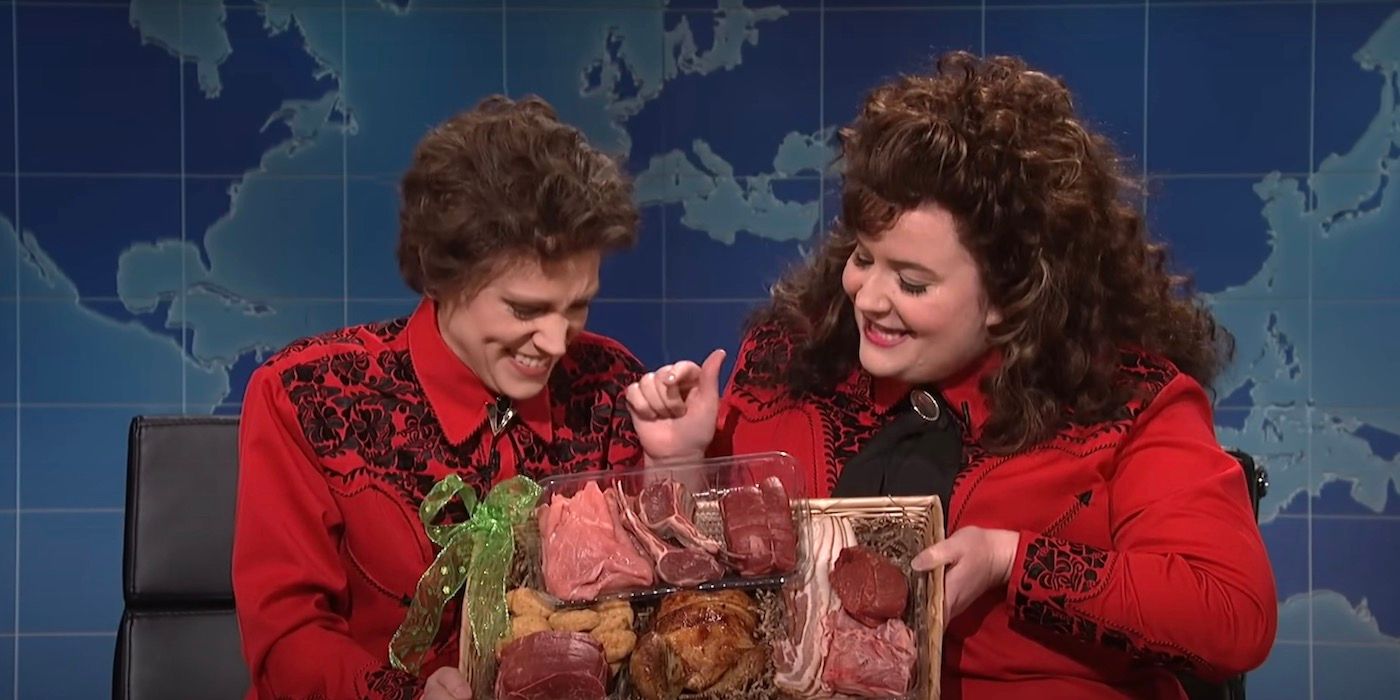 Kate McKinnon and Aidy Bryant are holding up a basket of meat. 