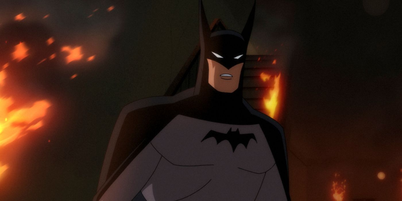 Batman looking concerned with a flaming building in his background in Batman Caped Crusader