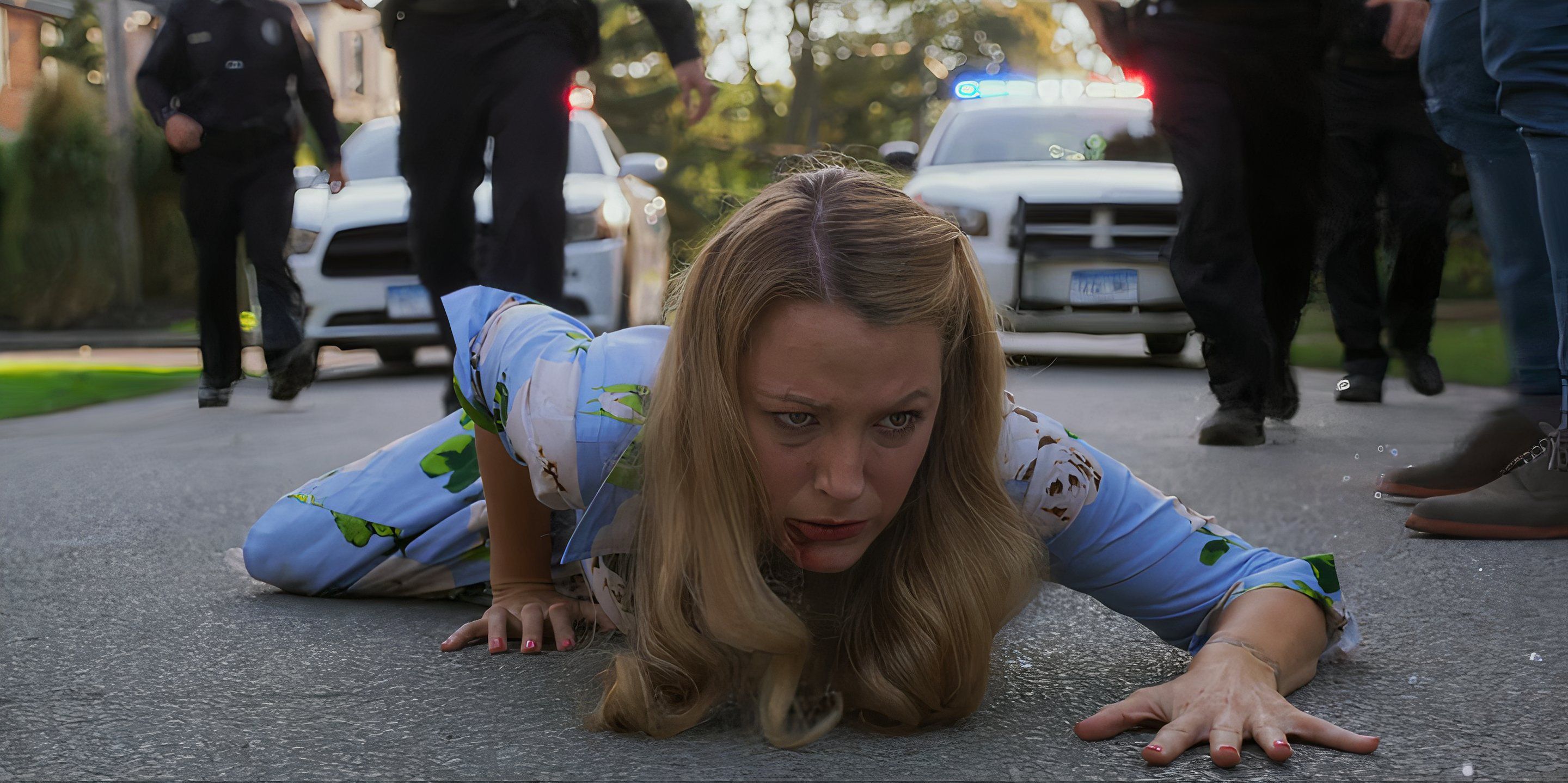 Emily (Blake Lively) rasteja no chão enquanto os policiais se aproximam atrás dela em A Simple Favor.