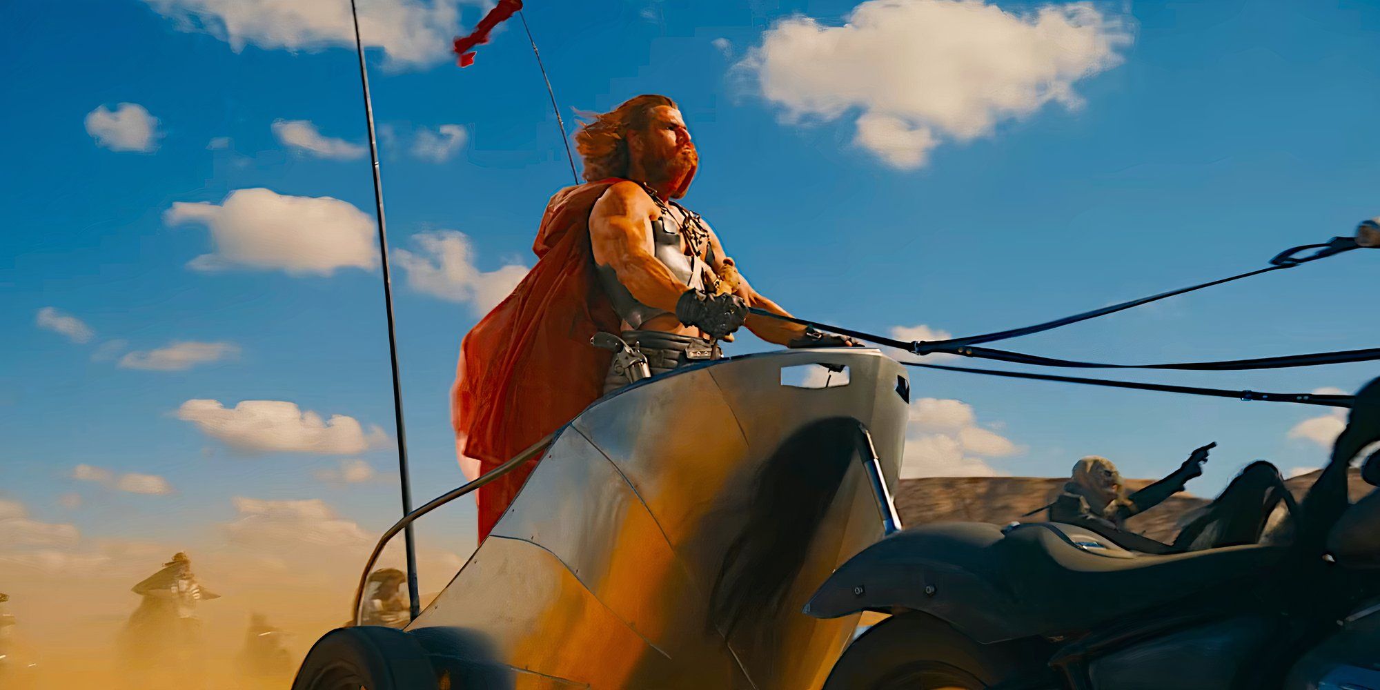 Chris Hemsworth as Dementus riding a metal chariot pulled by two motorcycles in an action scene from Furiosa: A Mad Max Saga