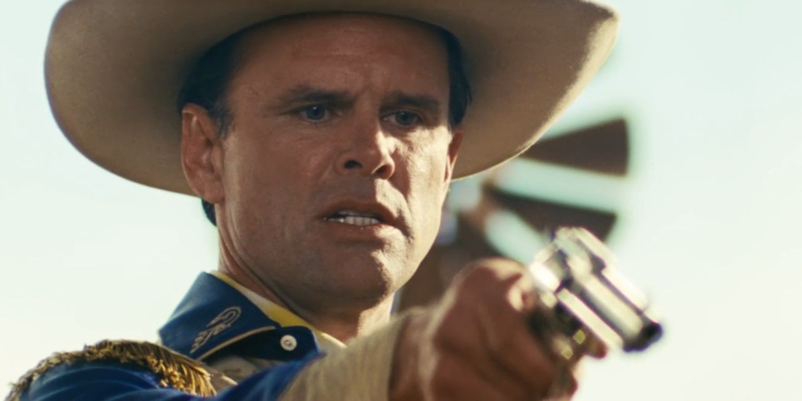 Cooper Howard (Walton Goggins) scowls and aims a revolver while wearing a cowboy hat in Fallout