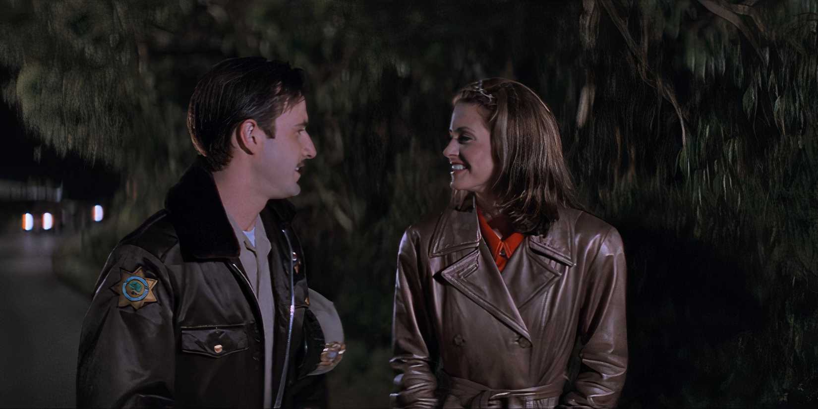 Gale (Courteney Cox) and Dewey (David Arquette) smile at each other as they walk together in Scream (1996).