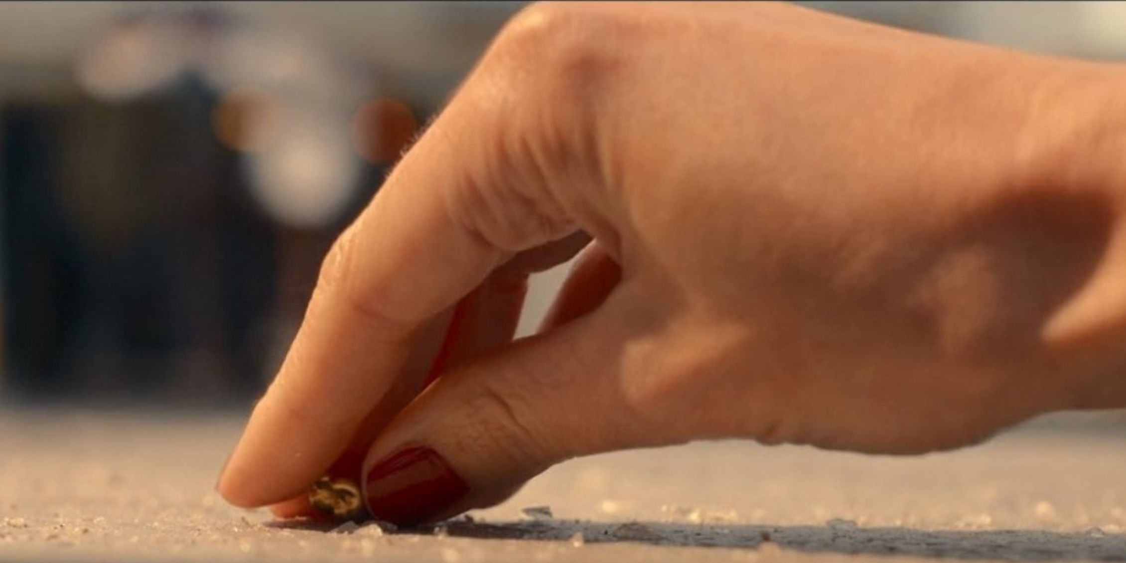 Mão misteriosa de mulher de Doctor Who com esmalte vermelho pegando um dente de ouro