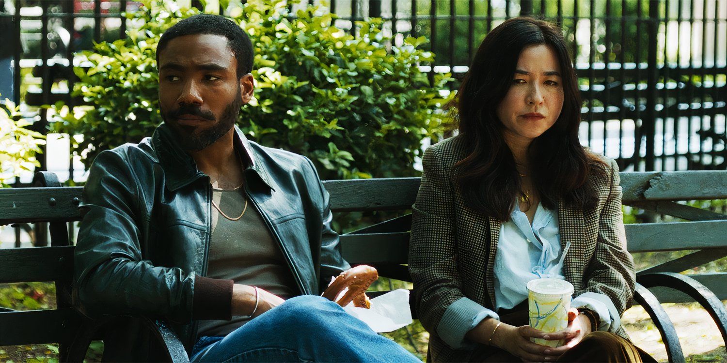 Donald Glover and Maya Erskine sitting on a bench in Mr & Mrs Smith