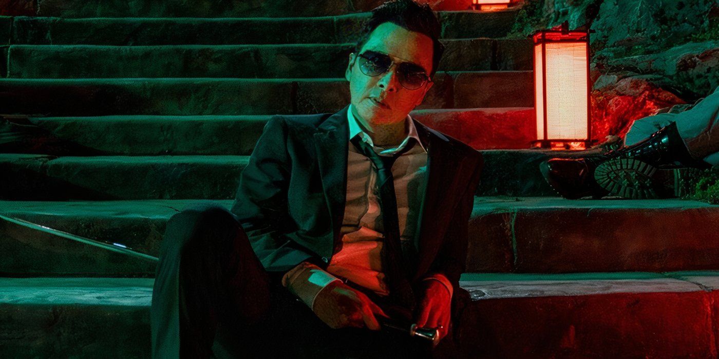 Donnie Yen as Caine sitting on stairs and wearing sunglasses in John Wick 4