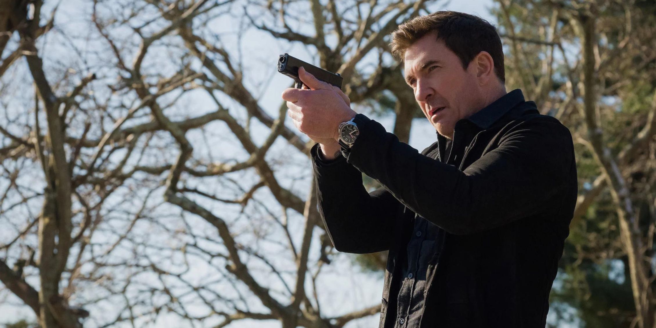 FBI Most Wanted Remy Scott (Dylan McDermott) holding a gun in the woods