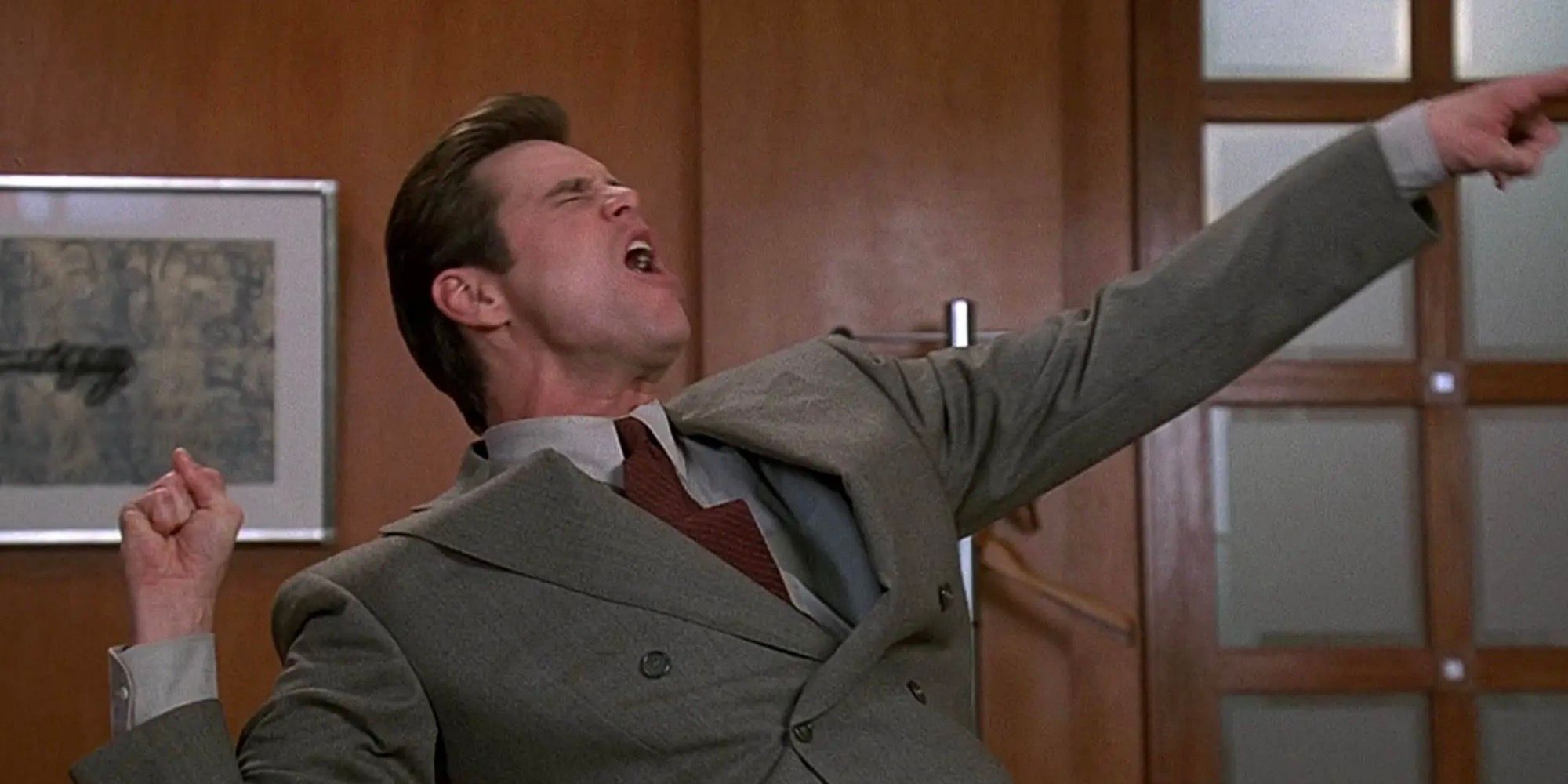 Jim Carrey está gritando com os braços estendidos. 