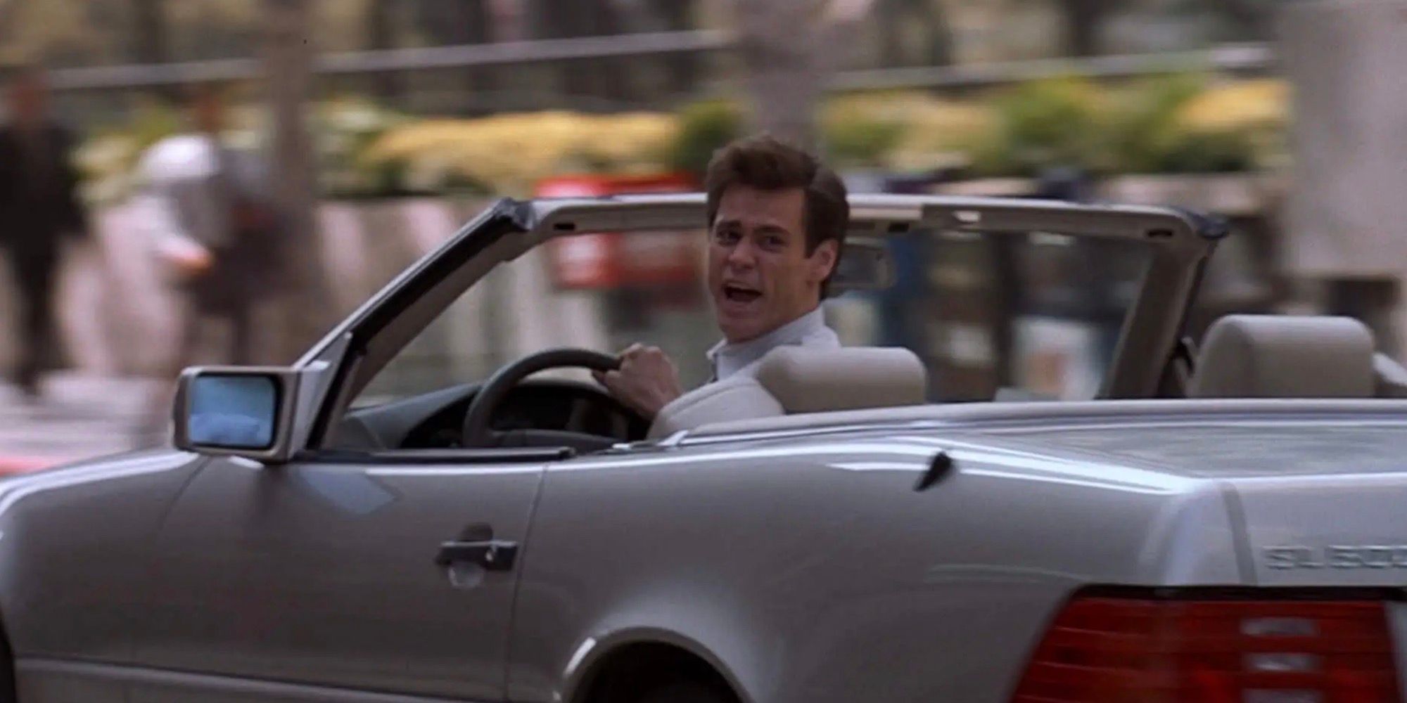 Jim Carrey está gritando e olhando para trás enquanto dirige. 
