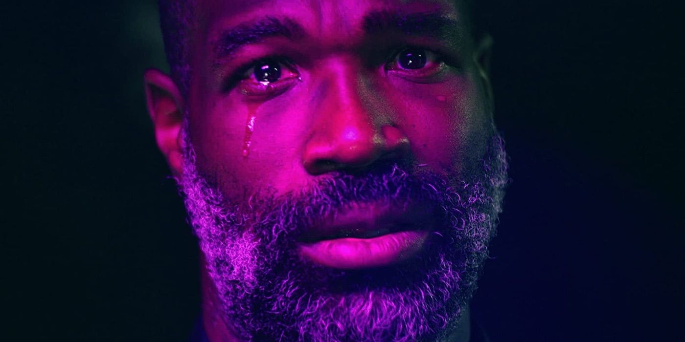 Tunde Adebimpe cries while bathed in purple light in Flood