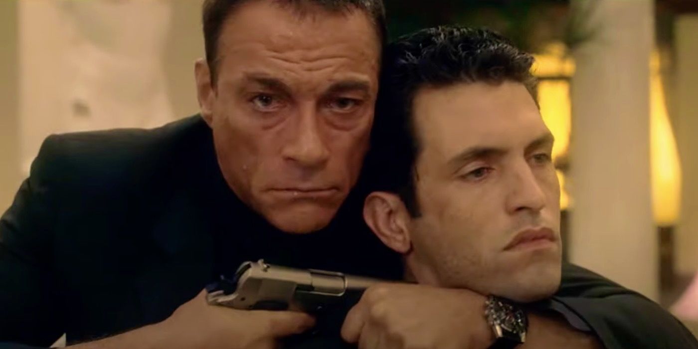 Frenchy (Jean-Claude Van Damme) holds a man at gunpoint in Frenchy