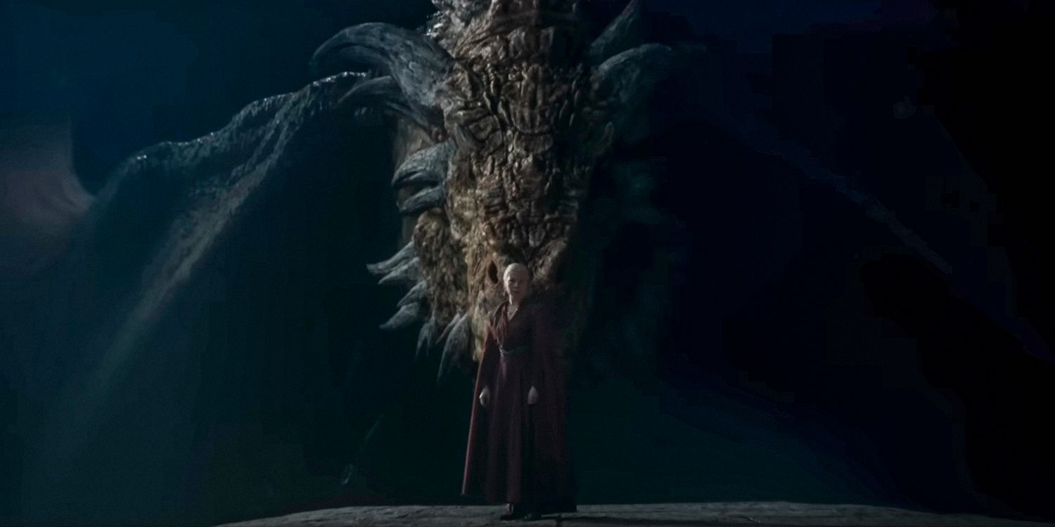 Queen Rhaenyra Targaryen (Emma D'Arcy) with a massive dragon emerging from the darkness in the background in House of the Dragon season 2