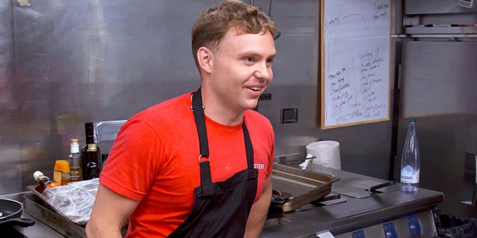 Chef Jack Luby from Below Deck Med season 8 in the galley wearing an apron and a red shirt