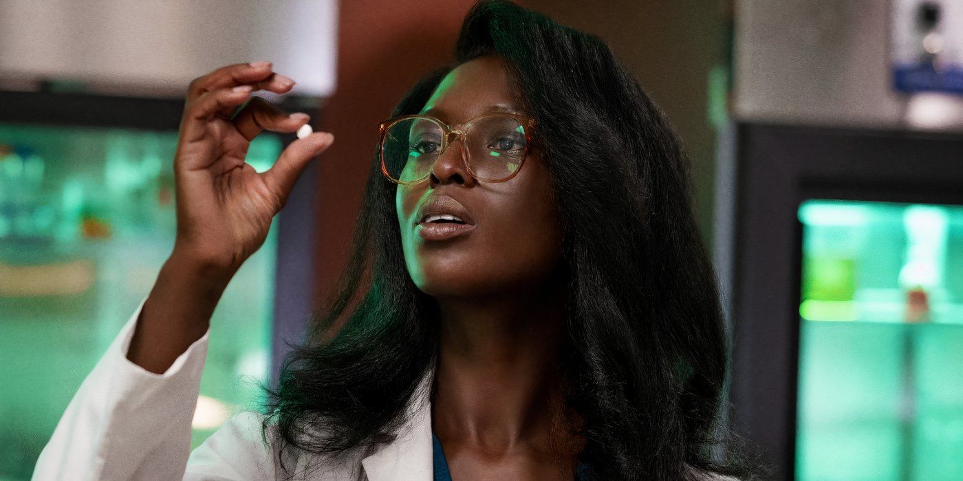 Jodie Turner-Smith as Winnie Richards holding up a Dylar pill and inspecting it in White Noise.-1