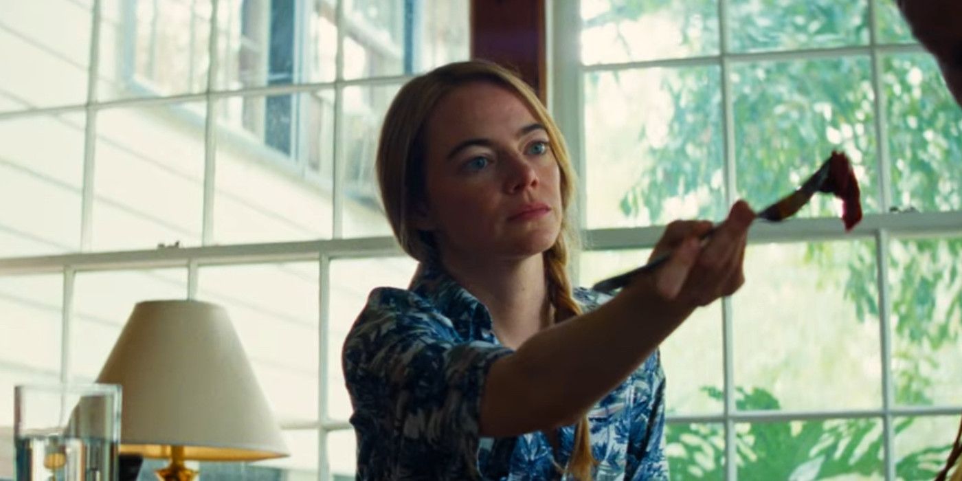 Emma Stone extending a fork to feed her husband in Kinds of Kindness