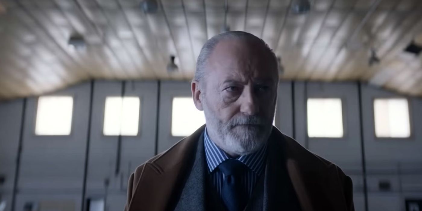 Liam Cunningham como Thomas Wade se preocupa por problemas corporales en un almacén en 3