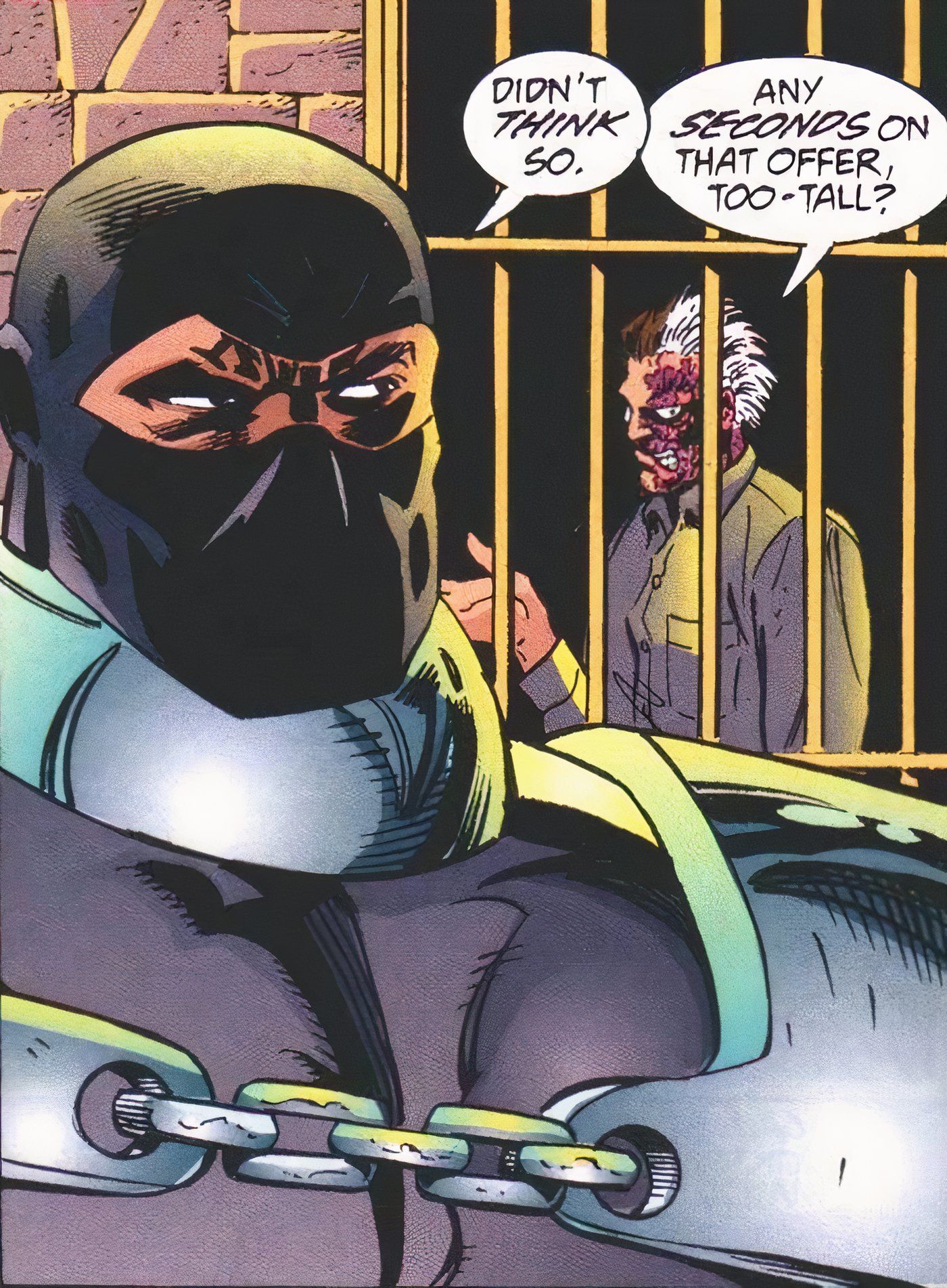 Batman villain Lock-Up talks to Two-Face through the bars of his cell in Arkham Asylum.