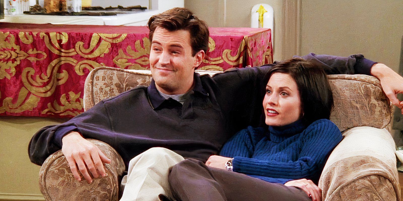 Monica and Chandler sitting in an armchair together on Friends