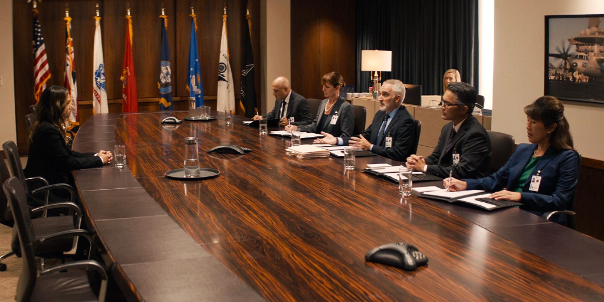 NCIS Glen Smith (Patrick Fischler) sits at a table with colleagues across from Jane Tennant (Vanessa Lachey)