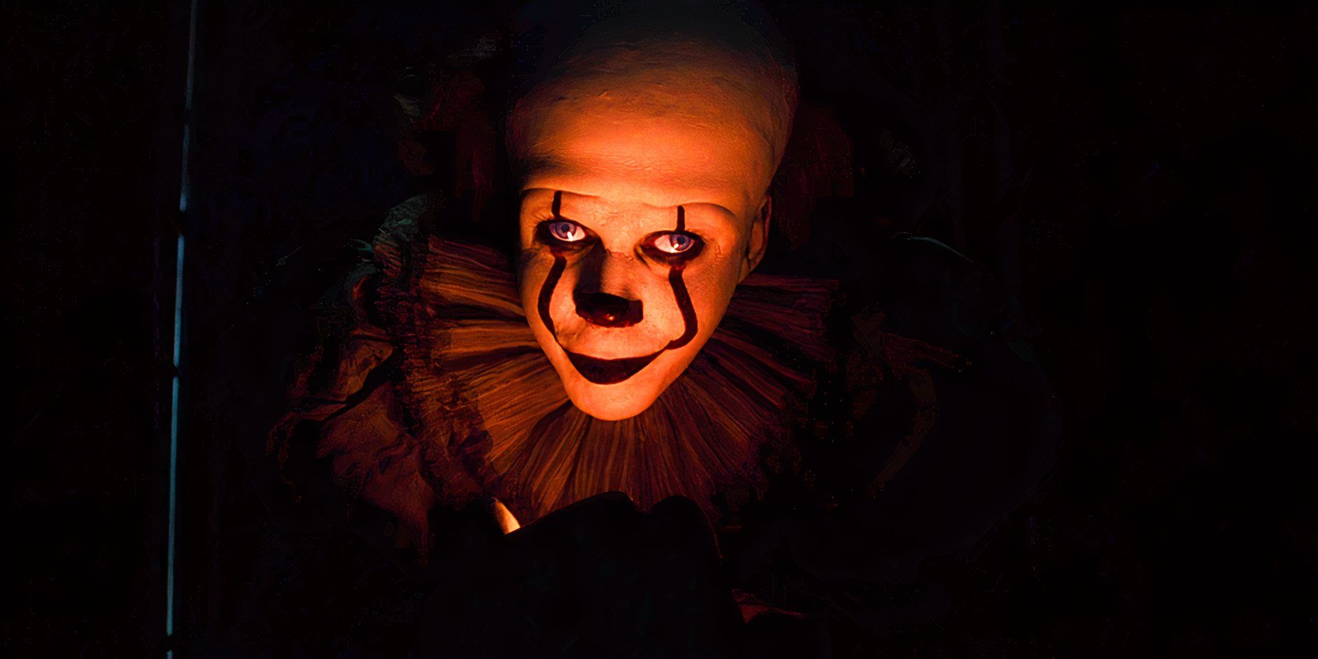 Pennywise lit with red light from below and surrounded by darkness in IT Chapter 2