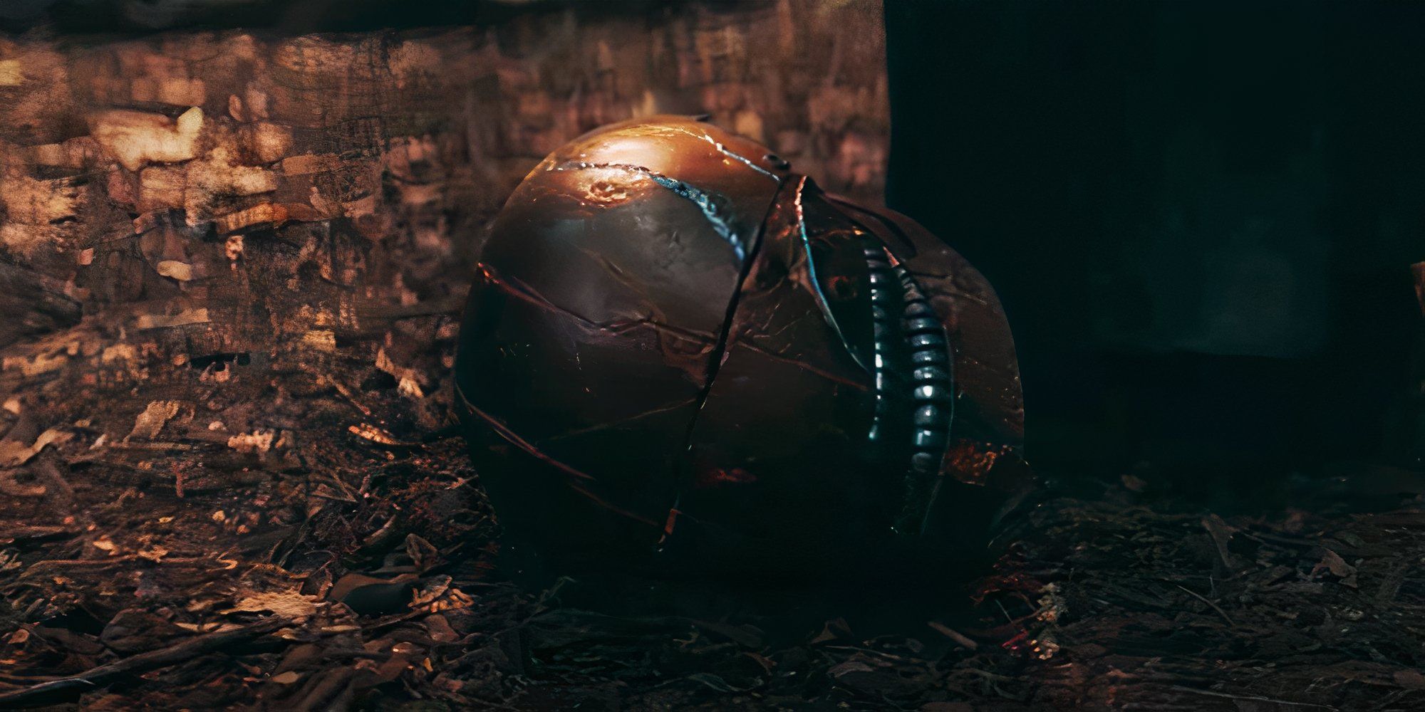 The mysterious Sith's helmet lays on the ground with a black cloak nearby