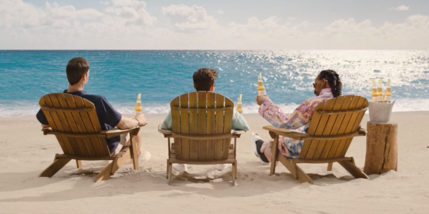 Snoop Dogg, Andy Samberg, and Eli Manning sitting in beach chairs looking out over the ocean in a Corona commercial.