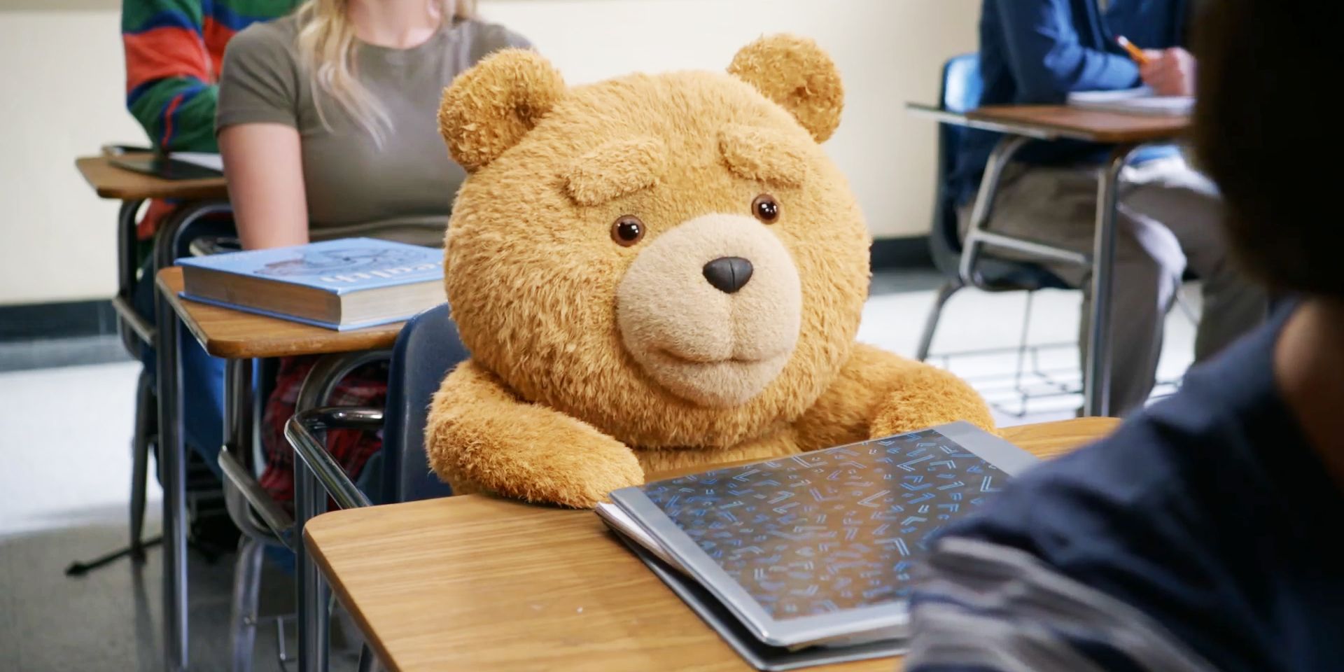 Ted the bear smiling as he sits at his desk in Ted season 1, episode 7