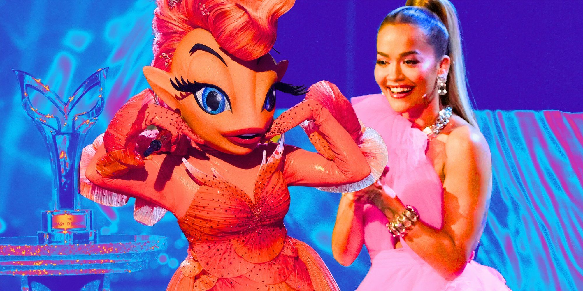 The Masked Singer&rsquo;s Goldfish holds her hands up by her face, and Rita Ora smiles while holding her hands together.