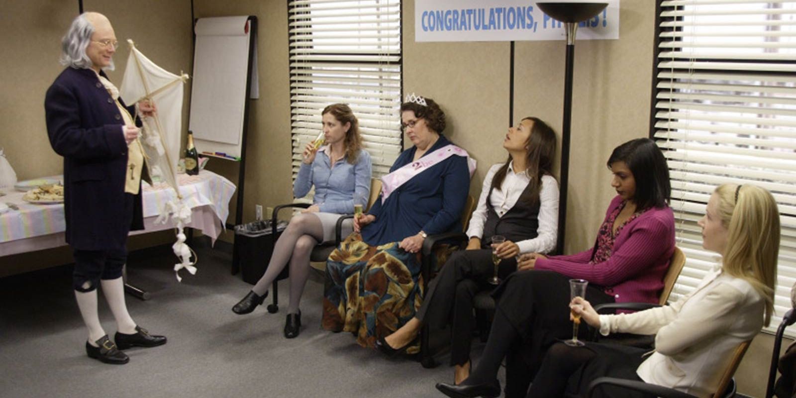 Pam, Phillis, Karen, Kelly, and Angela sit before a Benjamin Franklin impersonator in The Office