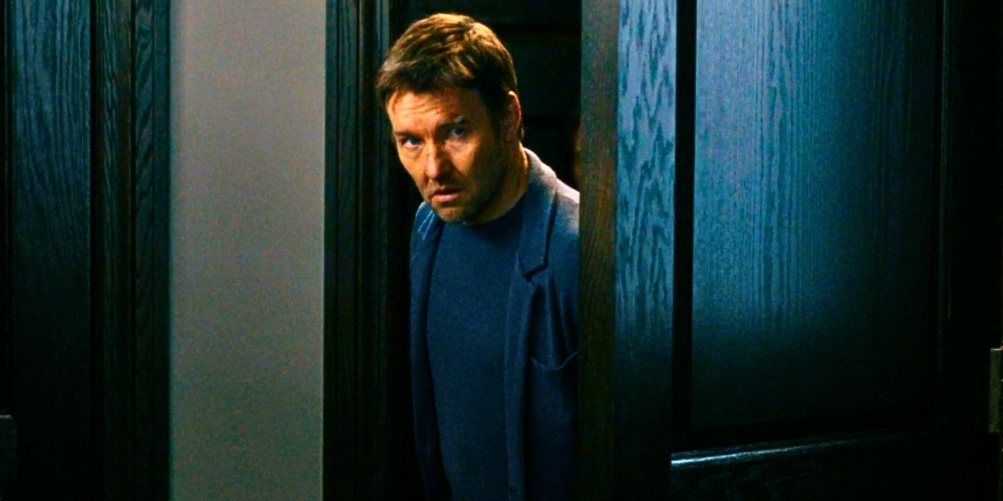 Joel Edgerton como Jason Dessen espiando por uma porta parecendo cauteloso em Dark Matter