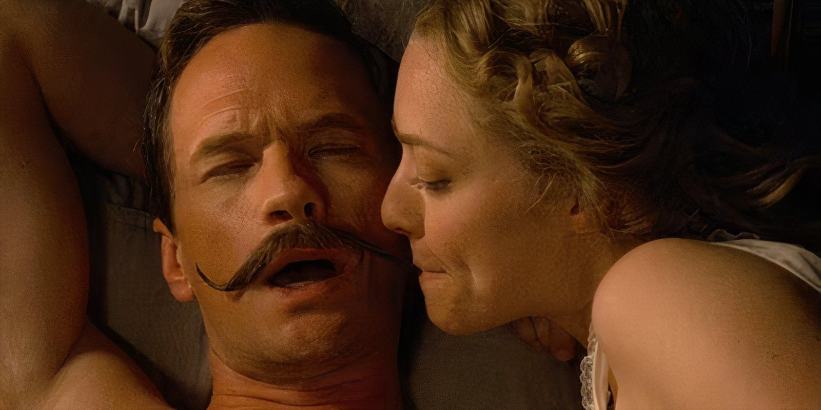 Louise puts Foy's mustache her mouth as they lie in bed in A Million Ways to Die in the West