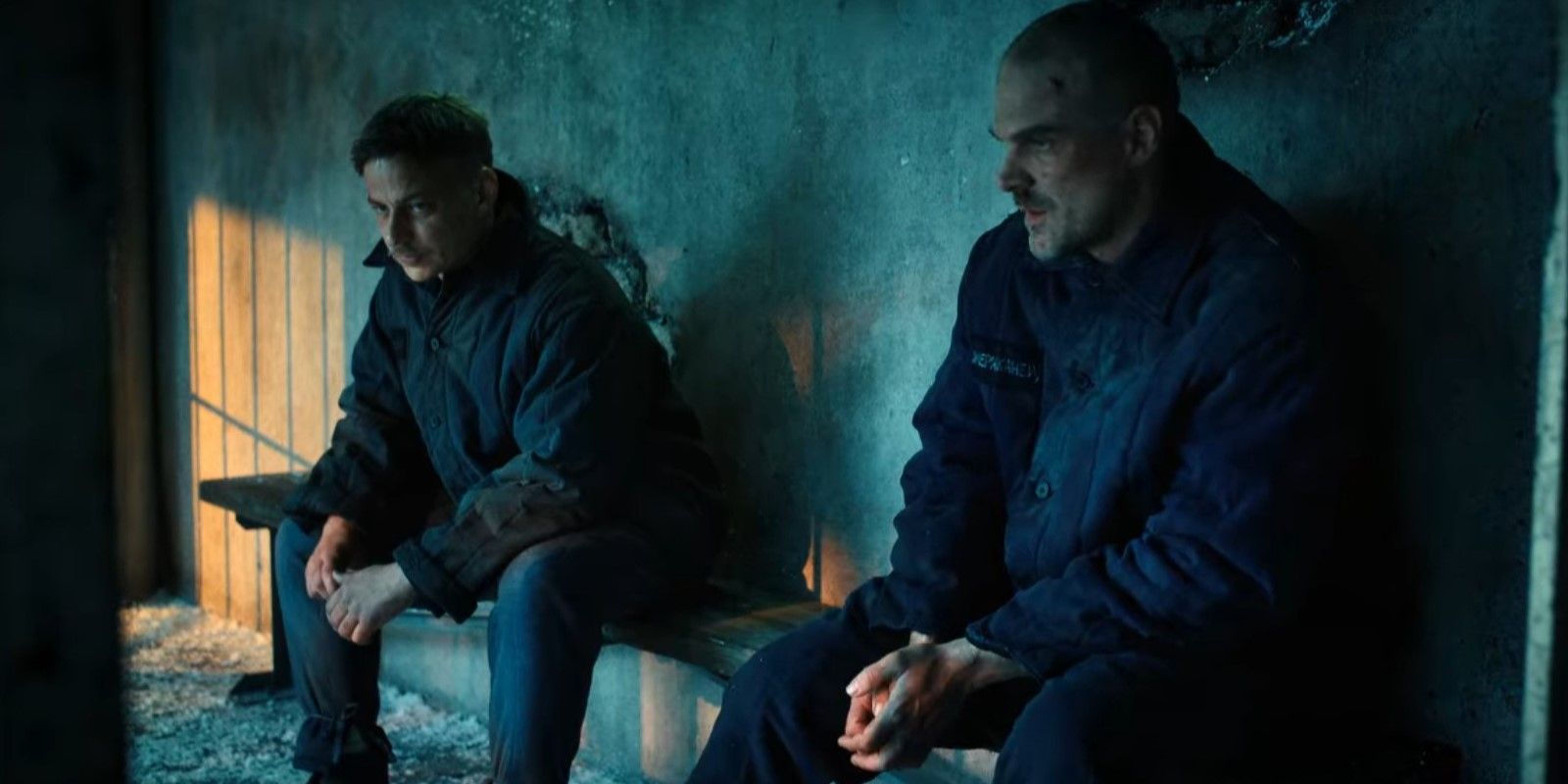 David Harbour as Jim Hopper sitting in a Russian prison cell next to his companion in Stranger Things