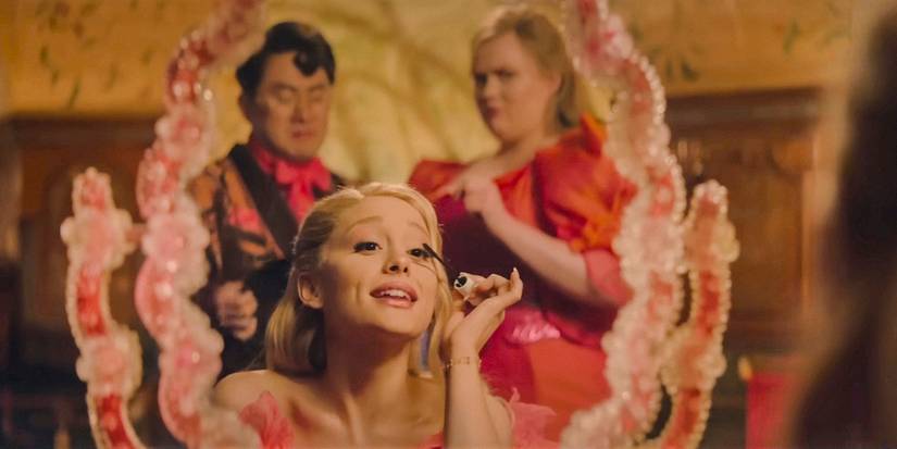 Glinda (Ariana Grande) putting on makeup, with ShenShen and Pfannee reflected in the mirror in Wicked