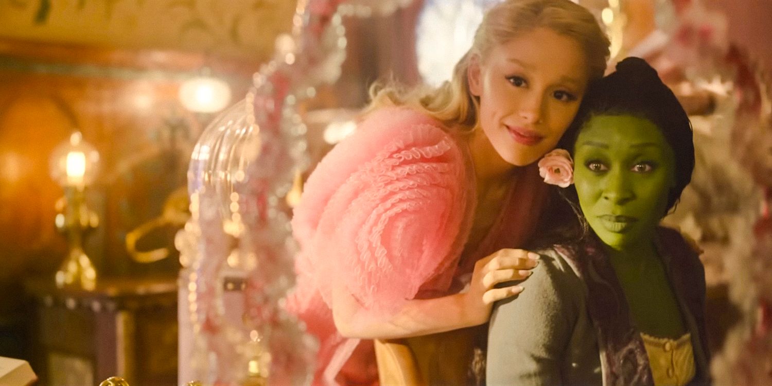 Elphaba (Cynthia Erivo) usando uma flor rosa no cabelo e Glinda (Ariana Grande) se olhando no espelho em Wicked 