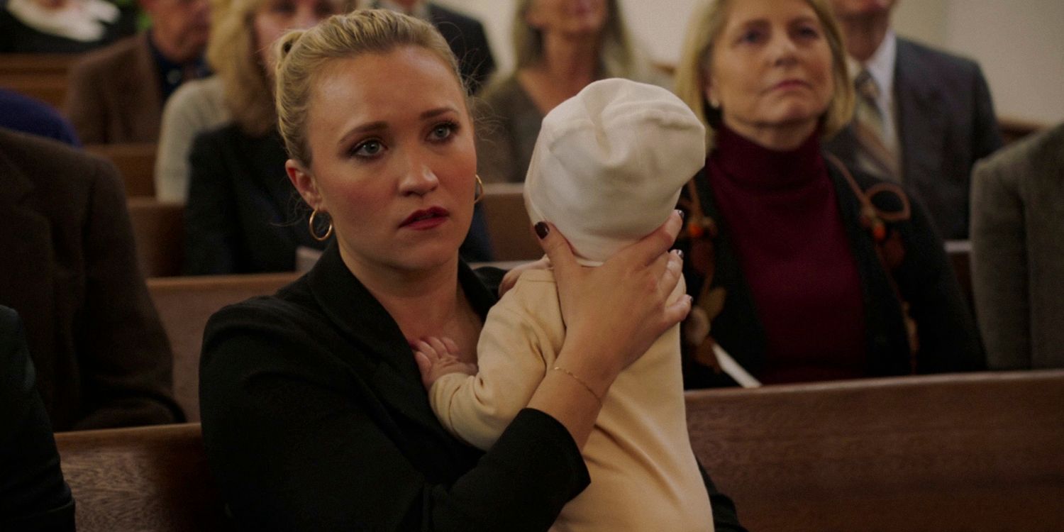 Mandy McAllister (Emily Osment) tinha uma expressão séria enquanto segurava seu bebê no funeral de George no episódio 13 da 7ª temporada de Young Sheldon