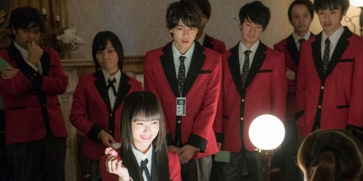 Minami Hamabe as Yumeko Jabami smiling with a group of characters standing around in the live-action Kakegurui