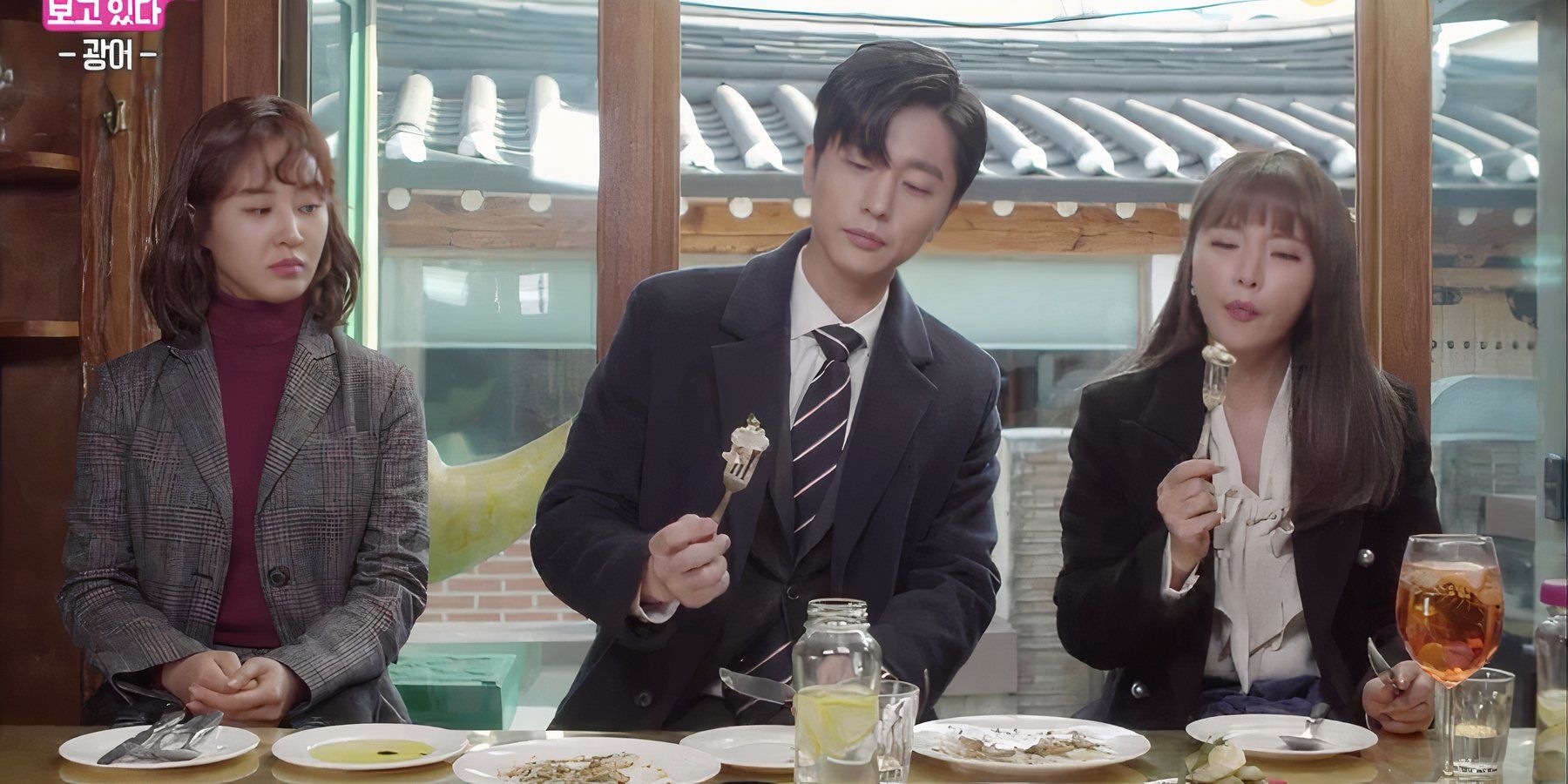 A woman watches a man and woman eat in the k-drama Dae Jang Geum Is Watching