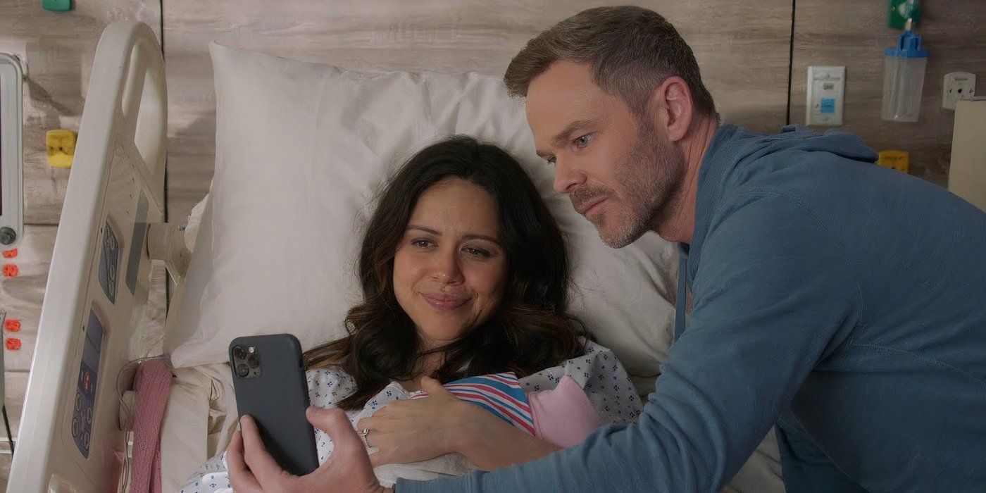 Angela (Alyssa Diaz) holding her baby while Wesley (Shawn Ashmore) holds up a phone for a selife in The Rookie.