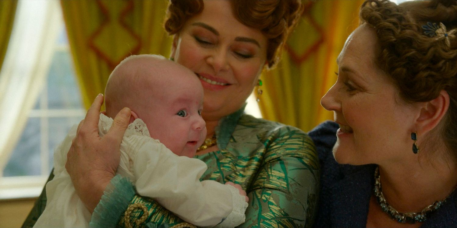 Lady Portia Featherington (Polly Walker) and Lady Violet Bridgerton (Ruth Gemmell) holding their grandson, the son of Penelope and Colin in Bridgerton season 3 episode 8