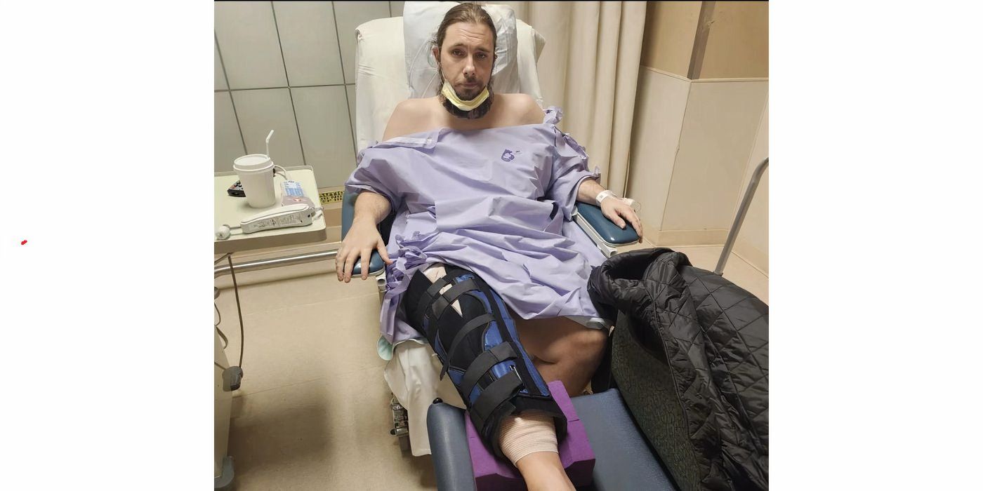 Colt Johnson In 90 Day Fiance in purple hospital gown lying on bed with a leg cast