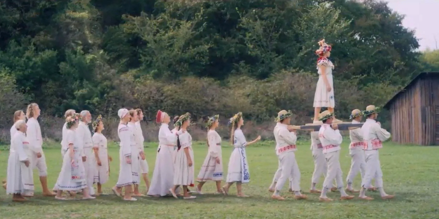 Florence Pugh as Dani being carried by cultists while her sister's face watches her on the background folliage in midsommar