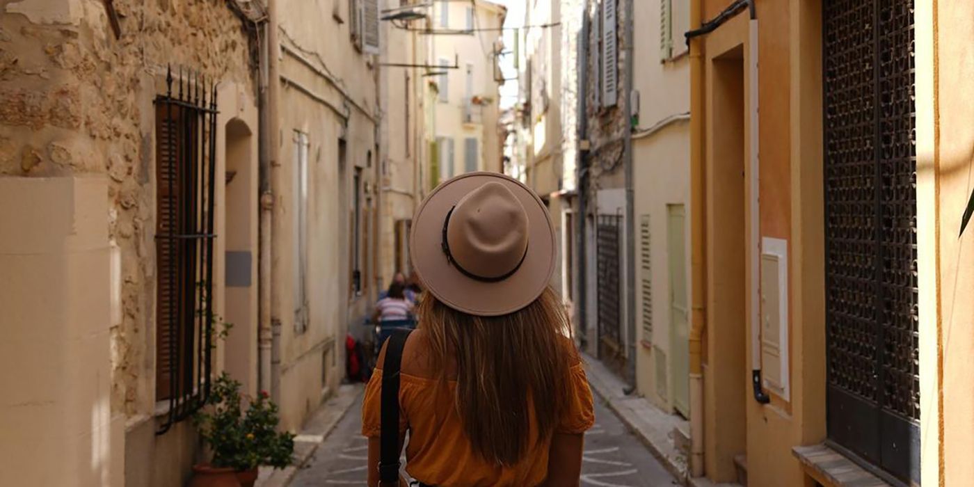 Gael Cameron from Below Deck Mediterranean facing away from the camera in a hat, walking down a narrow street in Spain.