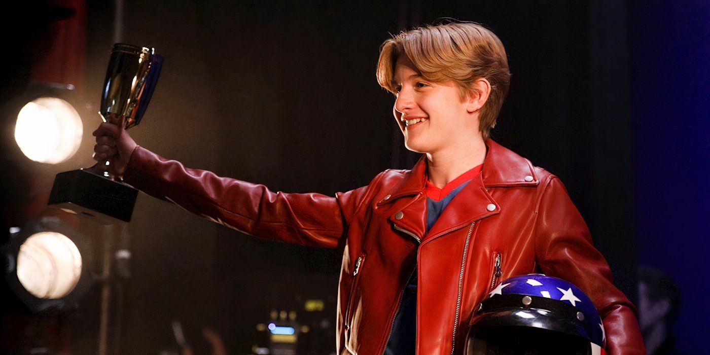 Christopher Paul Richards holds up a trophy while standing on stage 