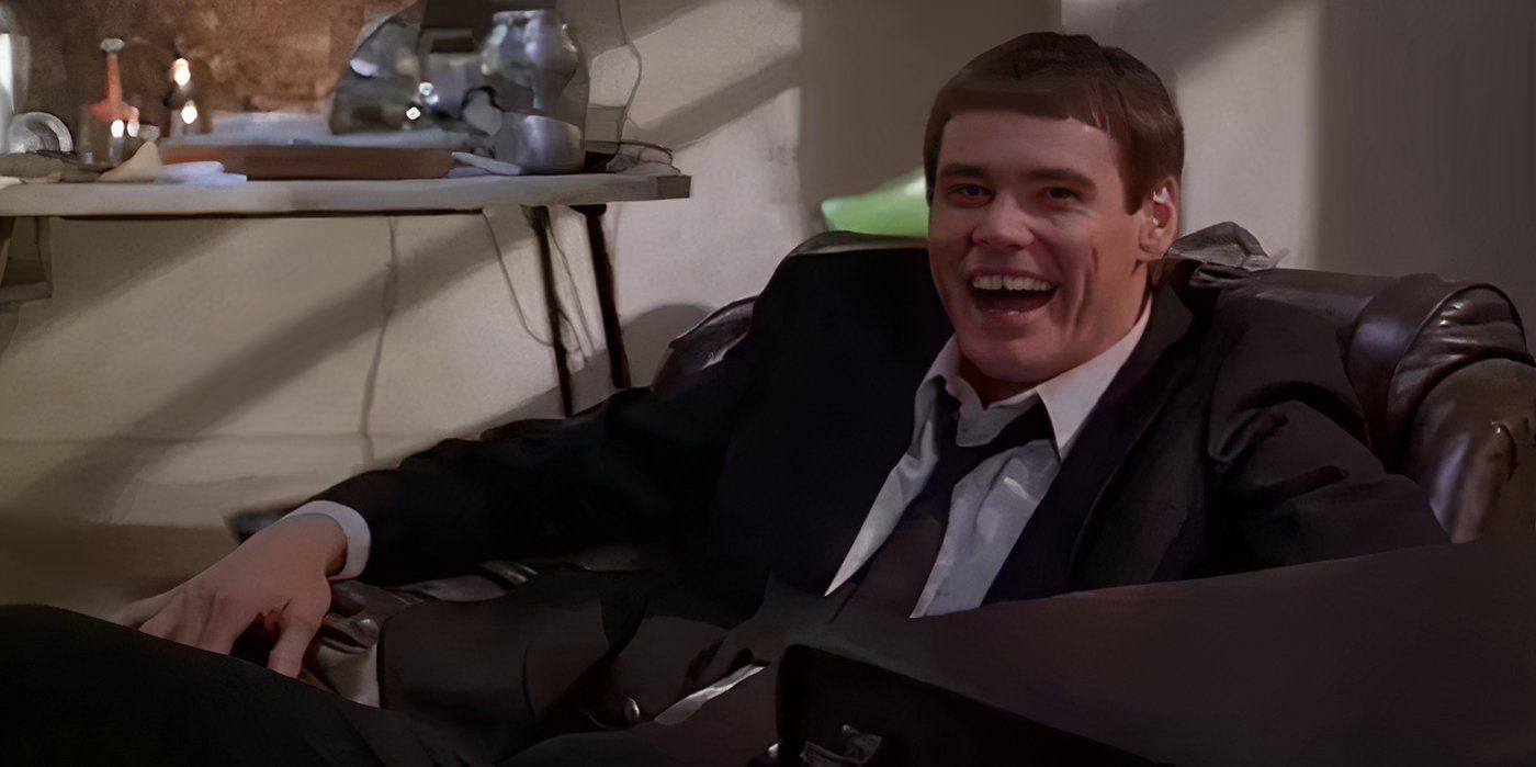 Jim Carrey as Lloyd Christmas sitting in a chair and laughing as Lloyd in Dumb and Dumber