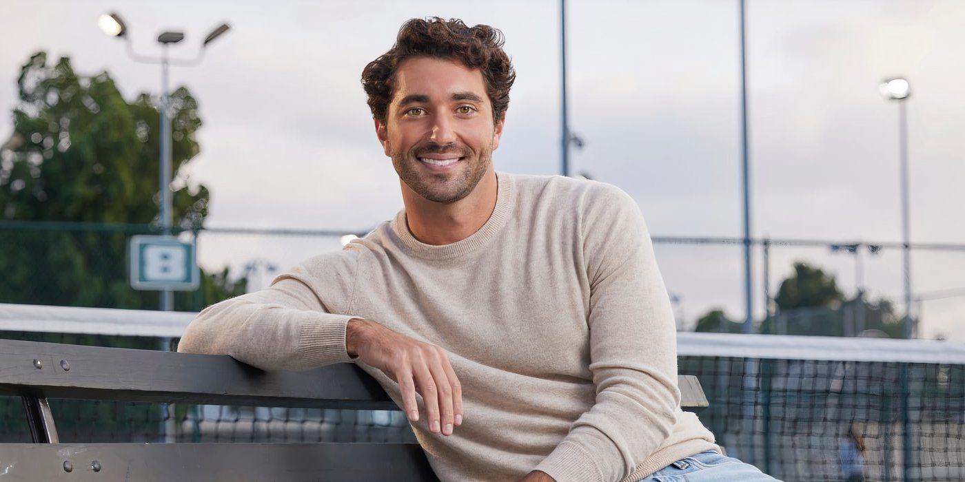 joey graziadei from the bachelor on a park bench in a beige sweater