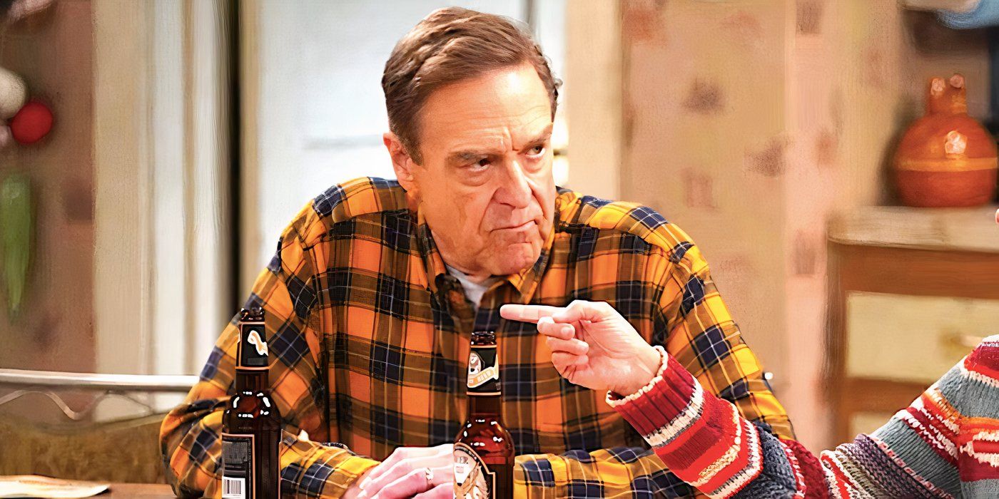 John Goodman's Dan sits at a kitchen table looking angry as someone points a finger in The Conners