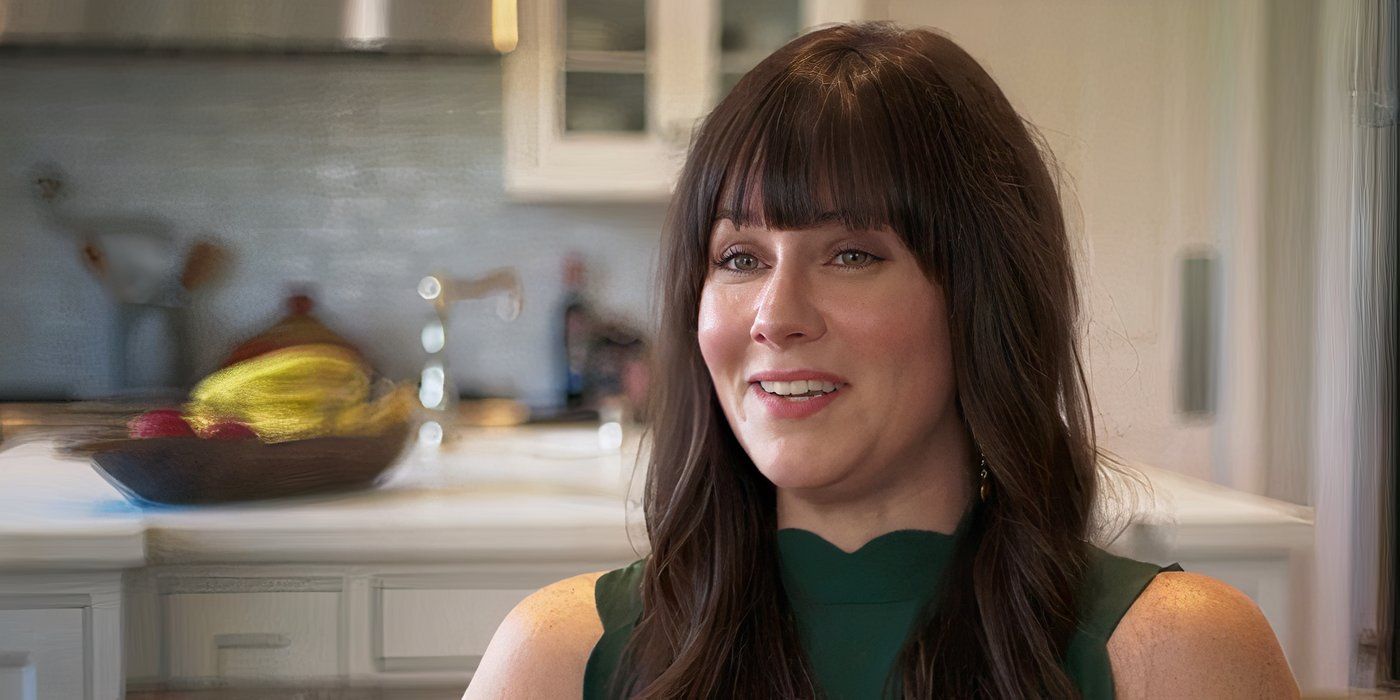 Katie Featherston se senta em uma cozinha para uma entrevista no documentário Atividade Paranormal.