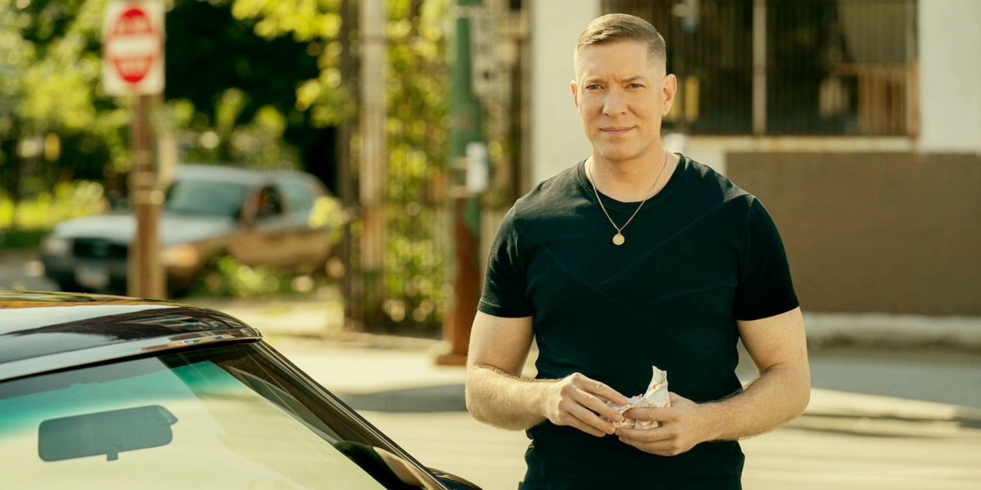 Tommy (Joseph Sikora) standing next to his car holding a burger on Power Book IV: Force Season 2